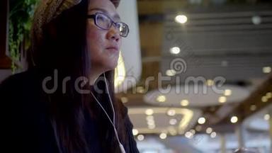 亚洲女人在商场里通过耳机听音乐。